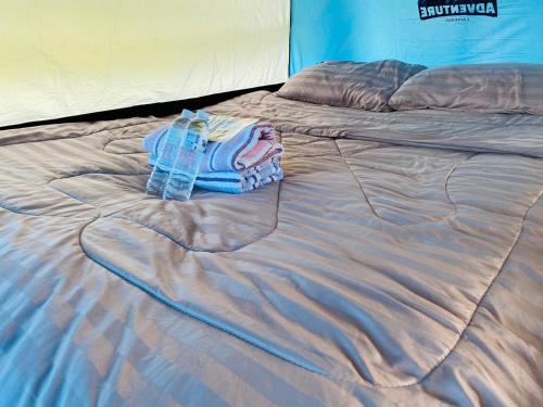 a bed with a blanket and a towel on it at PANAKLUEA Cottage & Crafts - พนาเกลือ in Ban Kham