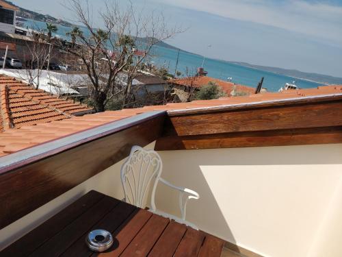 a wooden bench on a balcony with a view of the ocean at Orchis Hotel in Ayvalık