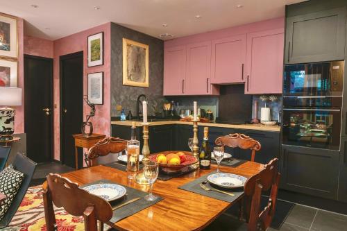 a kitchen with a wooden table and pink cabinets at The Iflissen Nest - Luxury Appartment in Lamorlaye