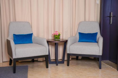 two chairs and a table with a vase of flowers at AG Hotel in Abu Dhabi