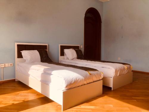 Habitación con 2 camas, paredes blancas y suelo de madera. en ART inn hotel, en Baku