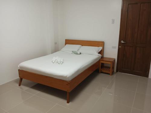 a bed with white sheets and a wooden headboard in a room at Angelito's Beach House 4 bedroom in General Luna