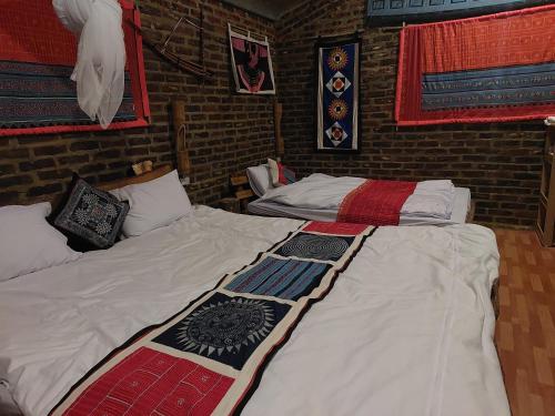 two twin beds in a room with brick walls at A La Homestay in Hòa Bình