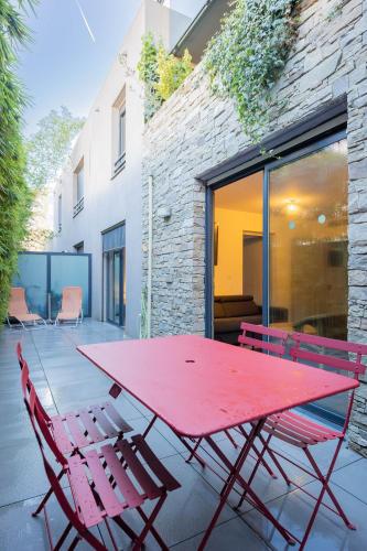 - une table de pique-nique rouge et 2 chaises sur la terrasse dans l'établissement Le Beau séjour, à Montpellier