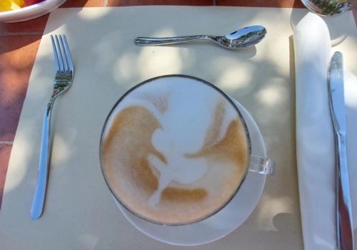 Un plato blanco con una taza de café sobre una mesa. en Hotel La Corte Rosada, en Villasimius
