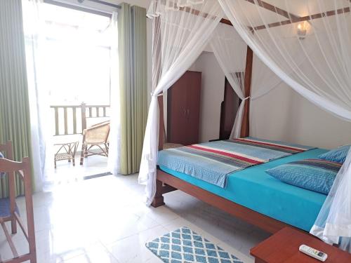 1 dormitorio con 1 cama con dosel y balcón en Villa 76, en Weligama