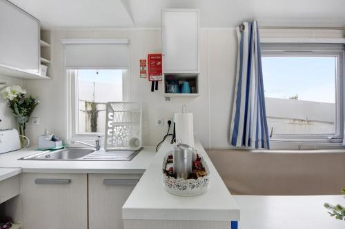 eine weiße Küche mit einem Waschbecken und einer Arbeitsplatte in der Unterkunft Villa Granja Sol 2 in São Félix da Marinha