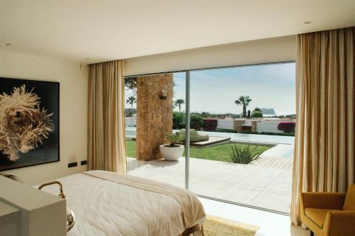 um quarto com uma cama e uma grande janela de vidro em Villa Sophie - Luxury Style & Sunset View em San Jose de sa Talaia