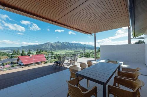 a patio with a table and chairs and a view of mountains at asoha in Minami Aso
