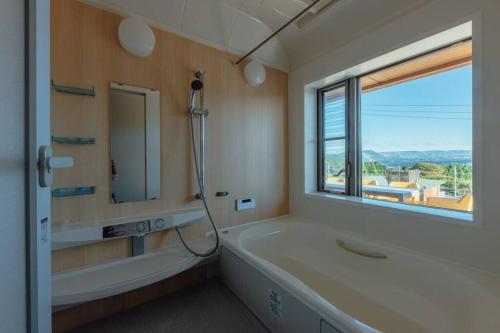 a bathroom with a tub and a sink and a mirror at asoha in Minami Aso