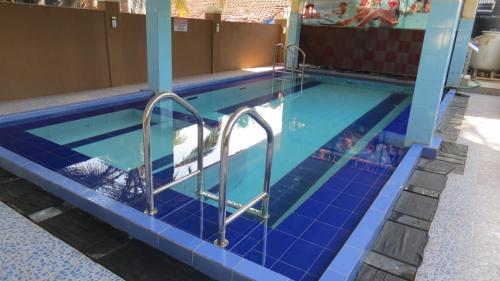 a swimming pool with blue tile and metal stairs in a building at BLUE MARINE BEACH REOSRT in Baga