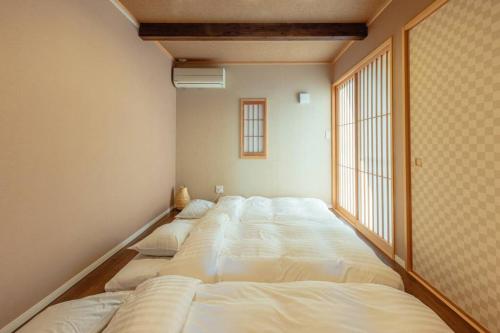 fila de camas en una habitación con ventana en asoha, en Minami Aso