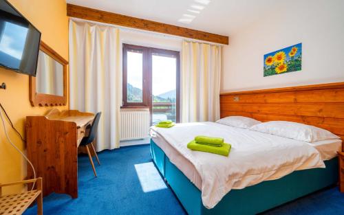 a bedroom with a bed with a television and a desk at Hotel Ondras z Beskyd in Ostravice