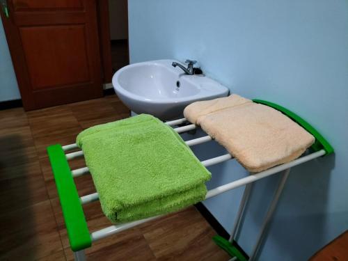 einen Handtuchhalter mit einem Waschbecken und einem grünen Handtuch in der Unterkunft Bito Homestay 