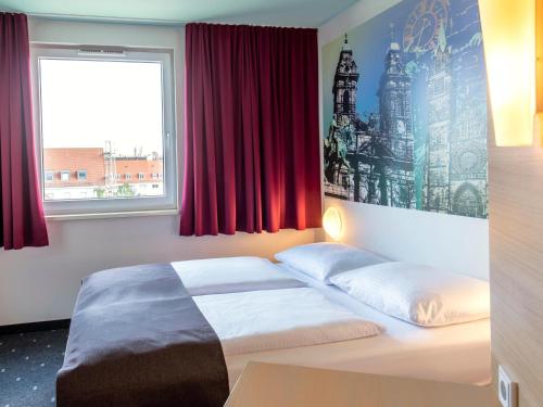 a bedroom with a bed and a window with red curtains at B&B Hotel Nürnberg-City in Nuremberg