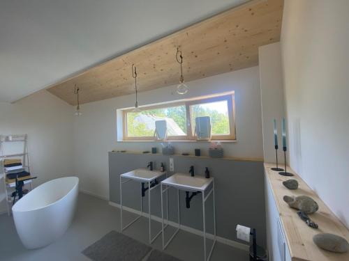 uma casa de banho com 2 lavatórios, uma banheira e uma janela em Das Lavendelhaus em Weißenstadt