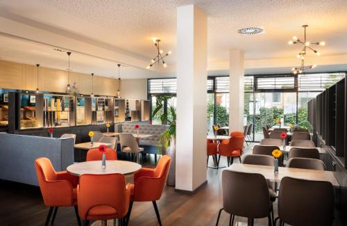 a restaurant with tables and chairs and windows at Leonardo Hotel Vienna Hauptbahnhof in Vienna