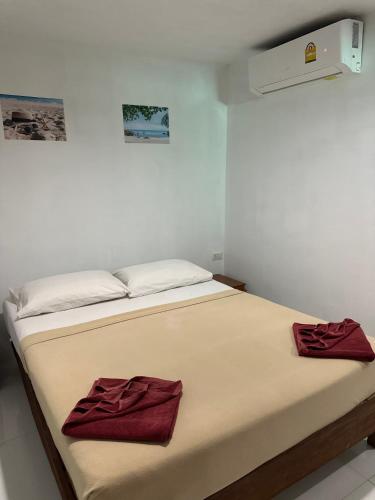 a bed in a room with two red towels on it at Bang sit Guest House in Phi Phi Don