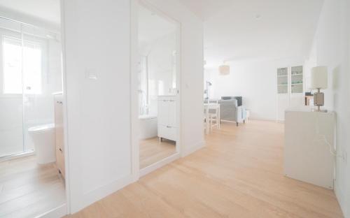 een witte kamer met witte muren en een houten vloer bij Apartamento Balbín IV in Gijón