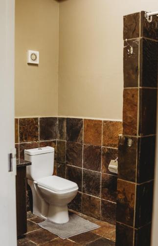 a bathroom with a toilet and brown tiled walls at Casa Leitao Lodge in Phalaborwa