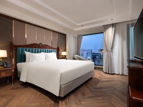 a bedroom with a white bed and a large window at L'Signature Hotel & Spa in Hanoi