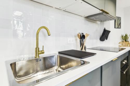 une cuisine avec un évier en acier inoxydable et un comptoir dans l'établissement Charmant logement au coeur du cours julien, à Marseille