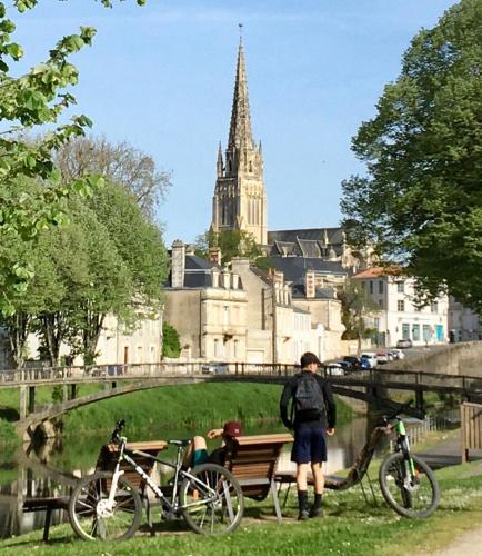 a person standing next to a bench and two bikes at La Frouardière, 3 gîtes de charme in Antigny