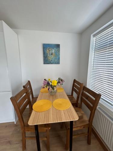a dining room table with chairs and flowers on it at Ecology North London Studios in East Barnet