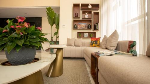 uma sala de estar com um sofá e um vaso de flores em Fourteen Hotel Ain Sebaa em Casablanca