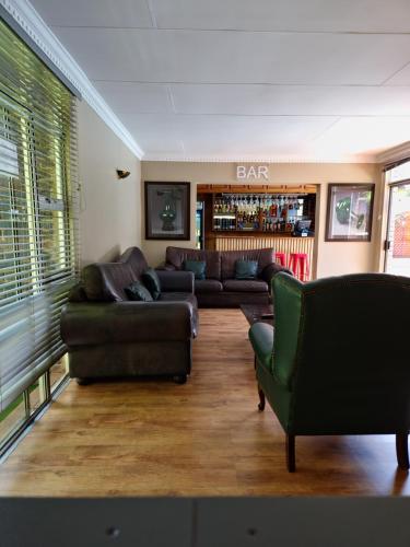 a living room with leather couches and a bar at FM GUEST LODGE Comfort, Tranquility & Peace of Mind in Johannesburg