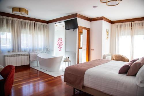 a bedroom with a bed and a bathroom with a tub at Hotel Spa Viña Real in Arévalo