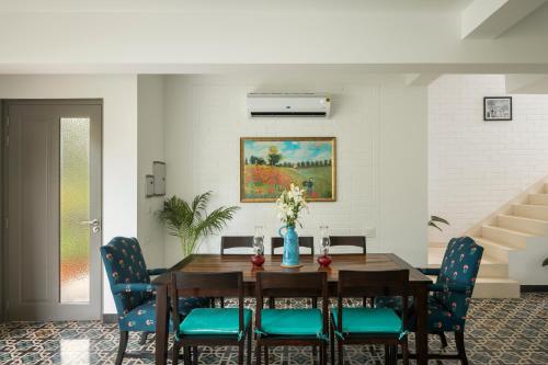 a dining room with a wooden table and blue chairs at El Rocio Estate 2bhk in Assagao with Common pool, Free Parking,8 min away from Vagator in Assagao