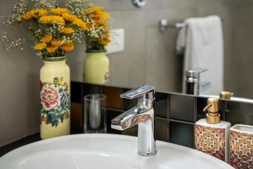 a bathroom sink with a faucet and a vase with flowers at El Rocio Estate 2bhk in Assagao with Common pool, Free Parking,8 min away from Vagator in Assagao