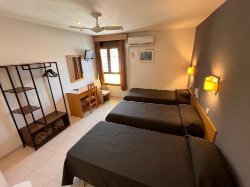 una camera d'albergo con 2 letti e una scrivania di Hostal Tarrés ad Anglés