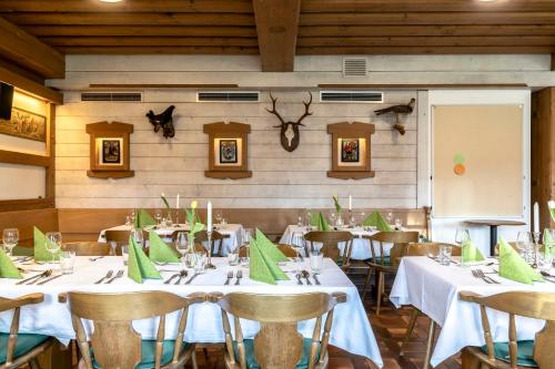 une salle à manger avec des tables, des chaises et des serviettes vertes dans l'établissement Hotel Alter Wirt, à Weyarn