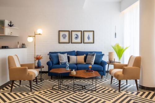 a living room with a blue couch and two chairs at El Rocio Estate 2bhk in Assagao with Common pool, Free Parking,8 min away from Vagator in Assagao