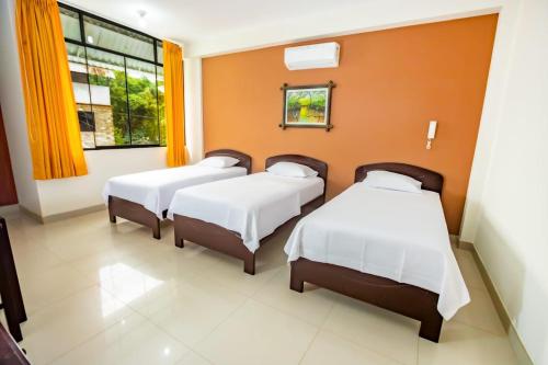 3 camas en una habitación con paredes de color naranja en Shilcayo Comfort Hospedaje, en Tarapoto