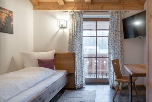 a bedroom with a bed and a desk and a window at Landhaus Hutter in Bad Heilbrunn