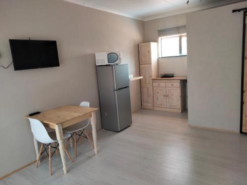 a small kitchen with a table and a refrigerator at Rustic Stone Lodge in Thabazimbi