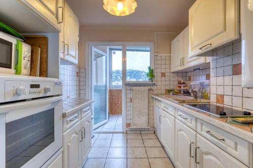 une cuisine avec des placards blancs et une grande fenêtre dans l'établissement F4 Traversant, 75m2 Avec Garages, à Sète