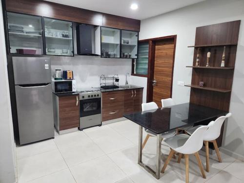 uma cozinha com uma mesa preta e cadeiras brancas em Casa M- 1 bedroom apartment Aquaview complex em Bijilo