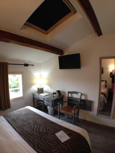 a bedroom with a bed and a desk and a mirror at Logis Hotel la Ferme in Avignon