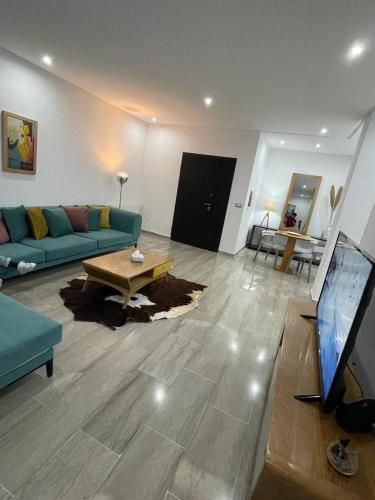 een woonkamer met een blauwe bank en een tafel bij Appartement l'aouina in El Aouina