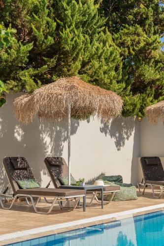two chairs and a umbrella next to a swimming pool at Natali Apartments by Estia in Malia