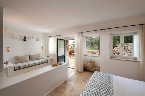 a white bedroom with a bed and a window at Hotel Masseria Fontanelle in Ugento