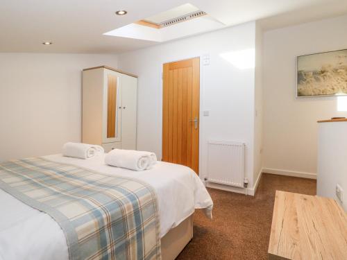 a white bedroom with a bed and a table at The Milking Parlour in Cranbrook