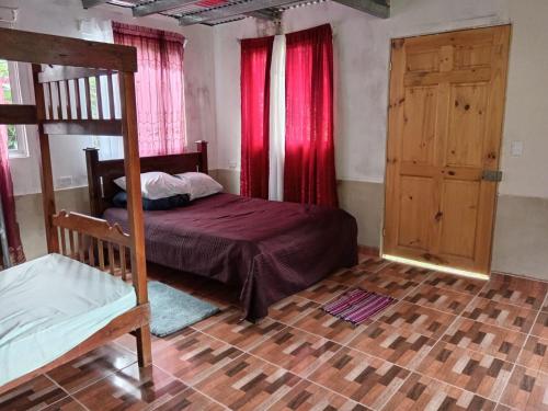 Schlafzimmer mit einem Bett mit roten Vorhängen und einer Tür in der Unterkunft Hospedaje Sauces - Cerro Chirripó in Herradura