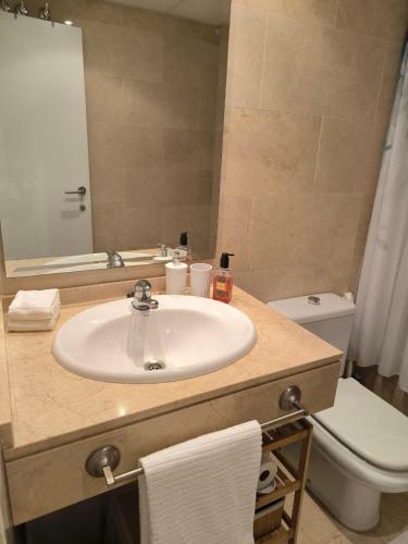 a bathroom with a sink and a toilet and a mirror at Balay Apartment Benidorm in Benidorm