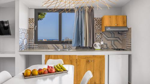 a kitchen with a table with a bowl of fruit on it at Natali Apartments by Estia in Malia