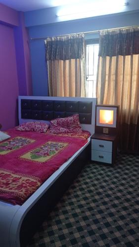 a bedroom with a bed and a television in it at Chandragiri Apartment in Khokna